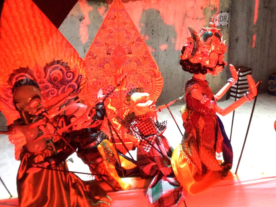 Puppen in roten Kostümen auf einer Bühne.