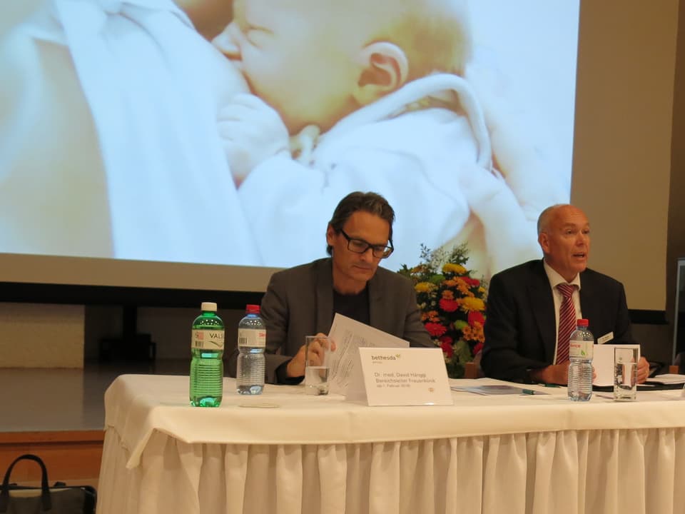 Thomas Rudin und David Hänggi vor Leinwand mit Säugling.