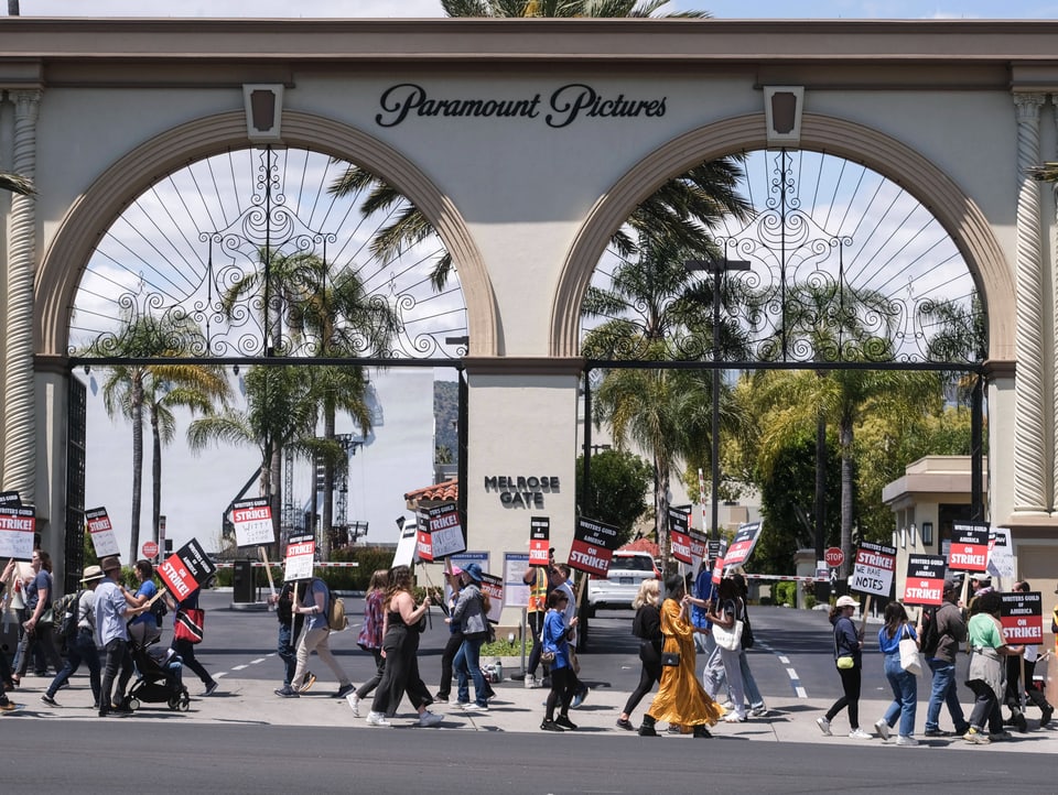 Eingangstor der Paramount Pictures in Hollywood, davor streikende Drehbuchautorenmit Schildern