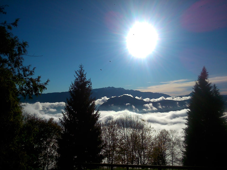 Morgensonne am blauen Himmel, unten liegen Nebelfelder über Lugano.