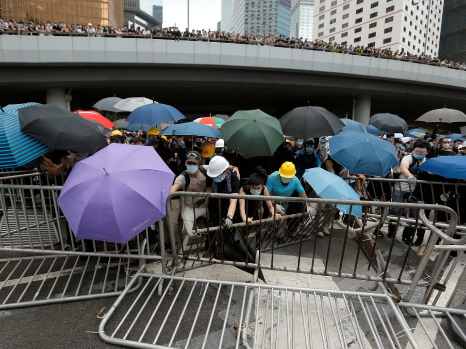 Demonstranten mit Regenschirmen bauen Barrikaden