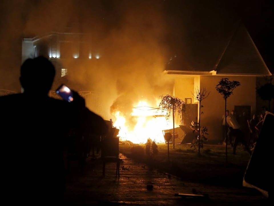 Ein brennendes Haus, davor bewaffnete Menschen. Bild stammt von 2019, als der ehemalige Präsident verhaftet werden sollte. 