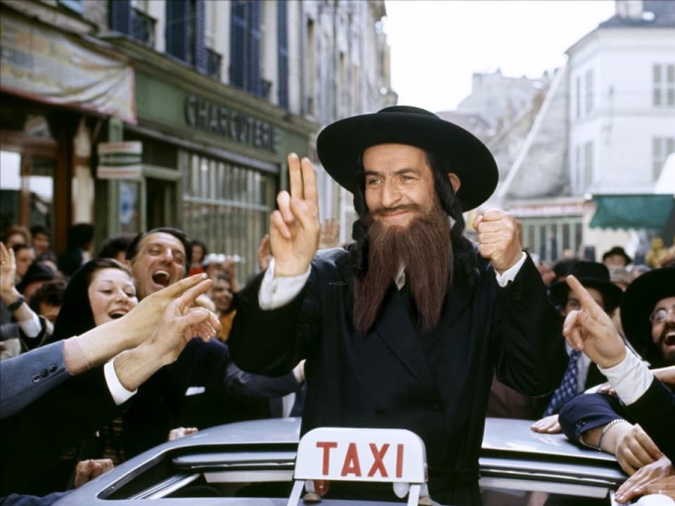 De Funès als Rabbi inmitten einer aufschauenden Menschenhorde.