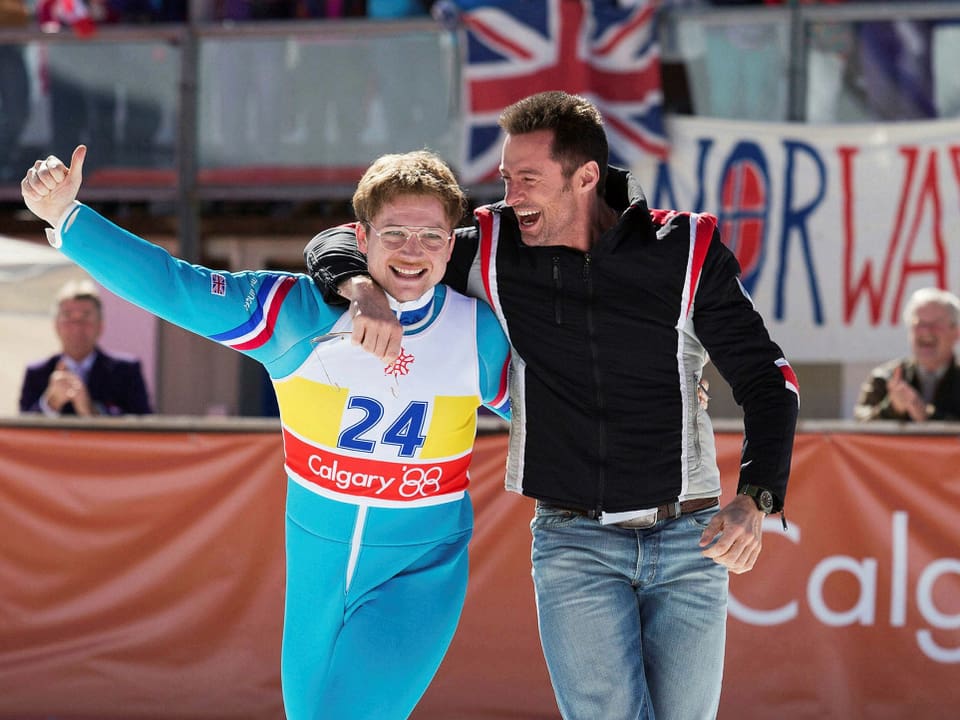 Eddie the Eagle wird von seinem Trainer umarmt. Beide freuen sich.