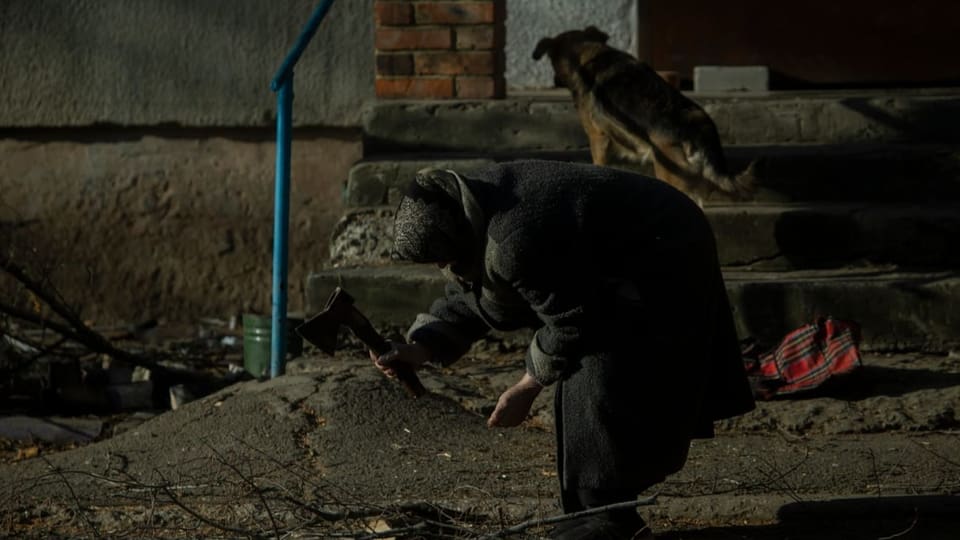 Ältere Frau hackt Brennholz in den Strassen von Bachmut, 27. Januar