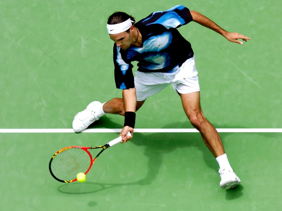 Federer in blei-weissem Shirt spielt einen Ball.