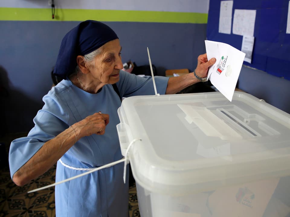 Nonne wirft ihr Wahlzettel in eine Urne.