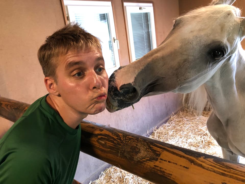 Reto Scherrer wird von einem Pferd geküsst.
