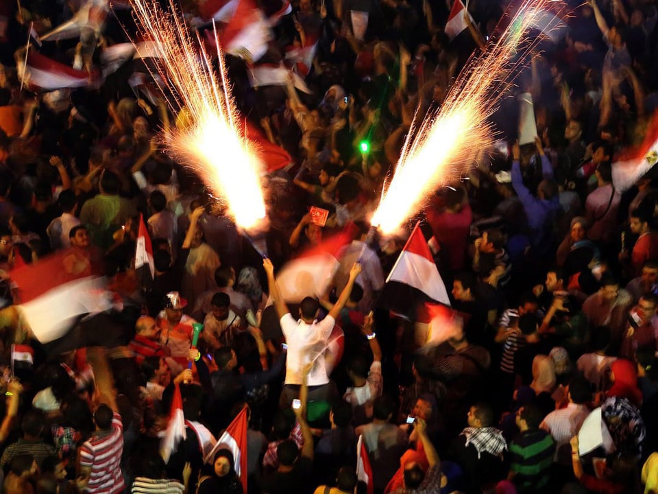 Menschen zünden inmitten der Massen Feuerwerke auf dem Tahrir Platz. (keystone)