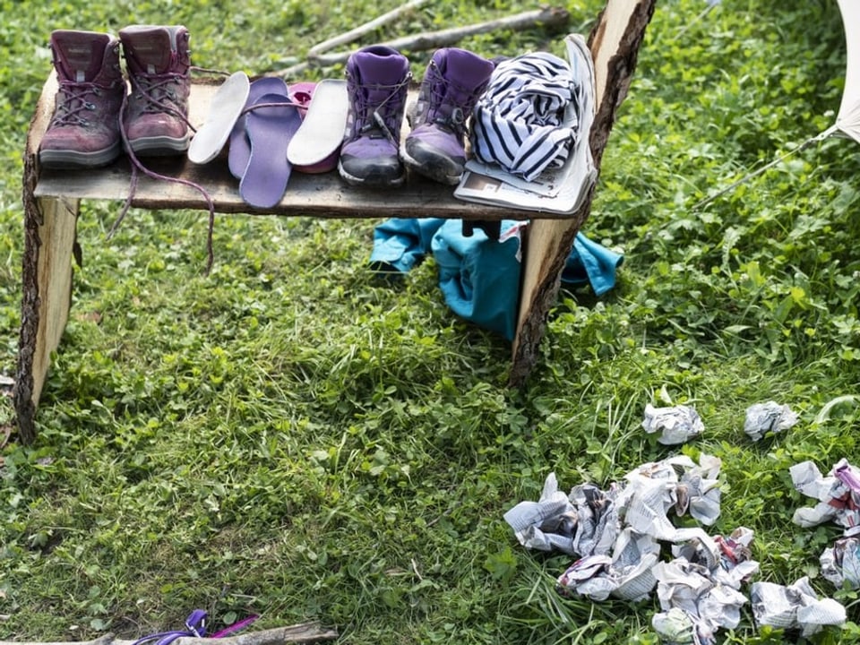 Nasse Schuhe trocknen vor einem Zelt.