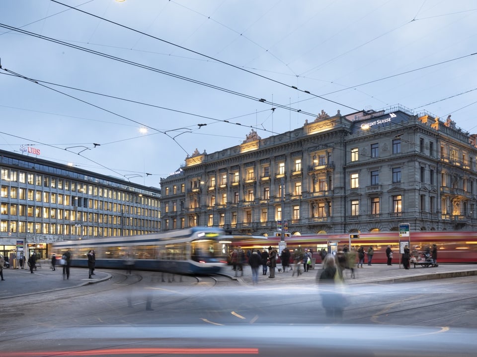 Blick auf den Paradeplatz in der Stadt Zürich. Es fahren Trams vorbei.