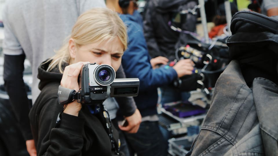 Eine junge Frau hält eine kleine Videokamera in der Hand