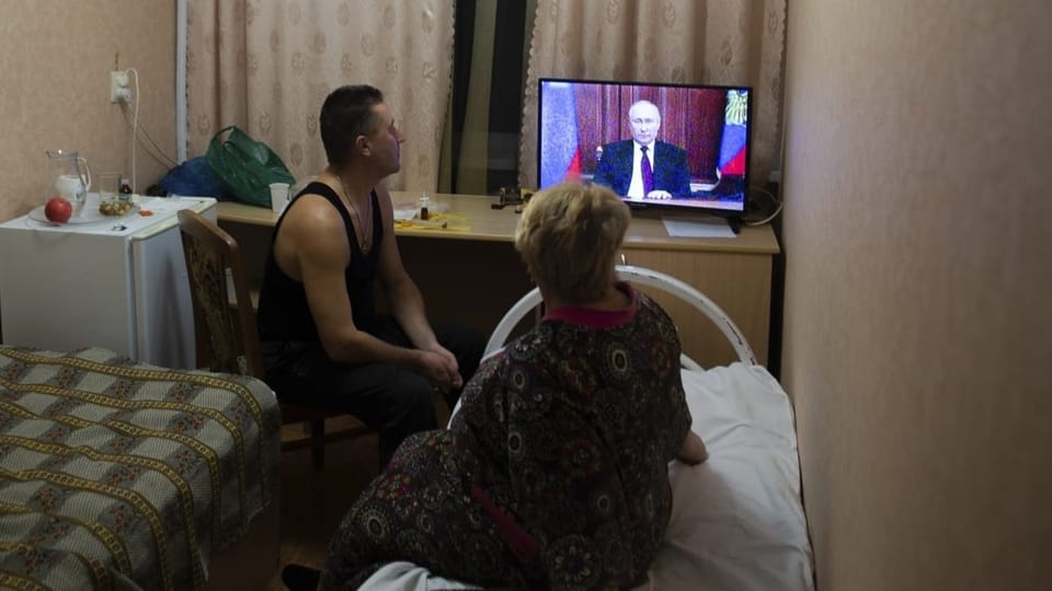 Ein Mann und eine Frau in einer Wohnung vor dem TV, Rede von Putin