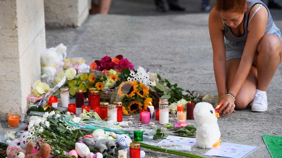 Eine Frau zündet eine Kerze an, um an die Opfer von Nizza zu gedenken.