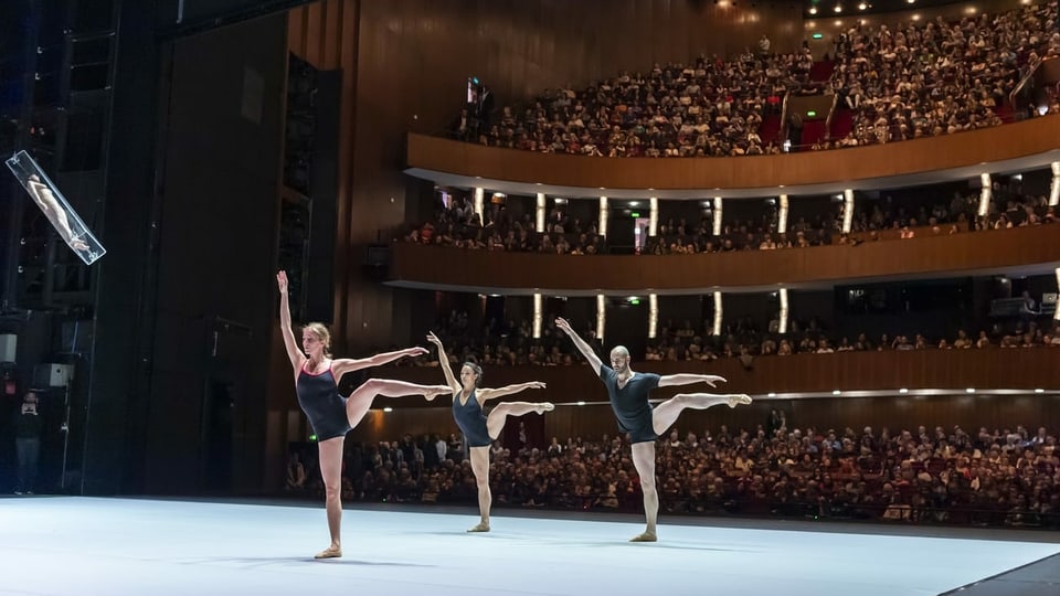 Drei Ballettänzer auf der Bühne und ein grosses Publikum im Hintergrund