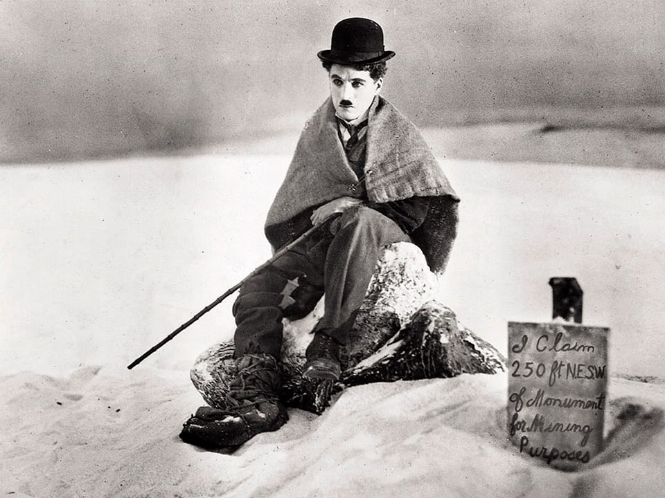 Charlie Chaplin im Schnee sitzend