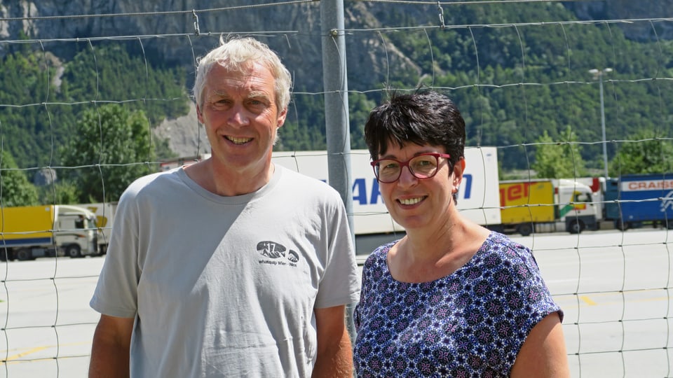 Ein Mann und eine Frau stehen vor einem hohen Zaun - im Hintergrund eine Autobahn