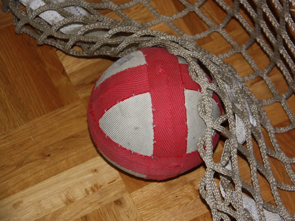Ein rot-weisser weicher Ball unter einem Tornetzt.