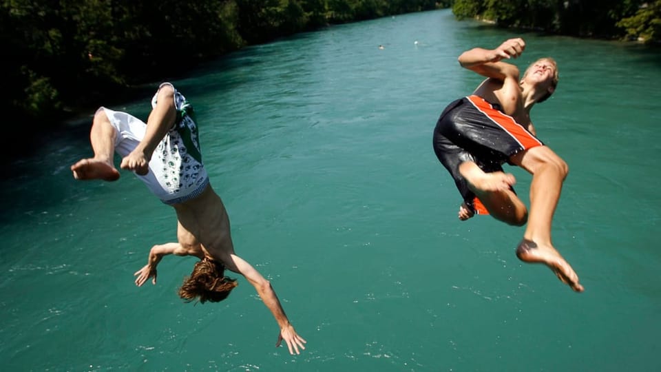 Zwei Personen springen in einen Fluss. 