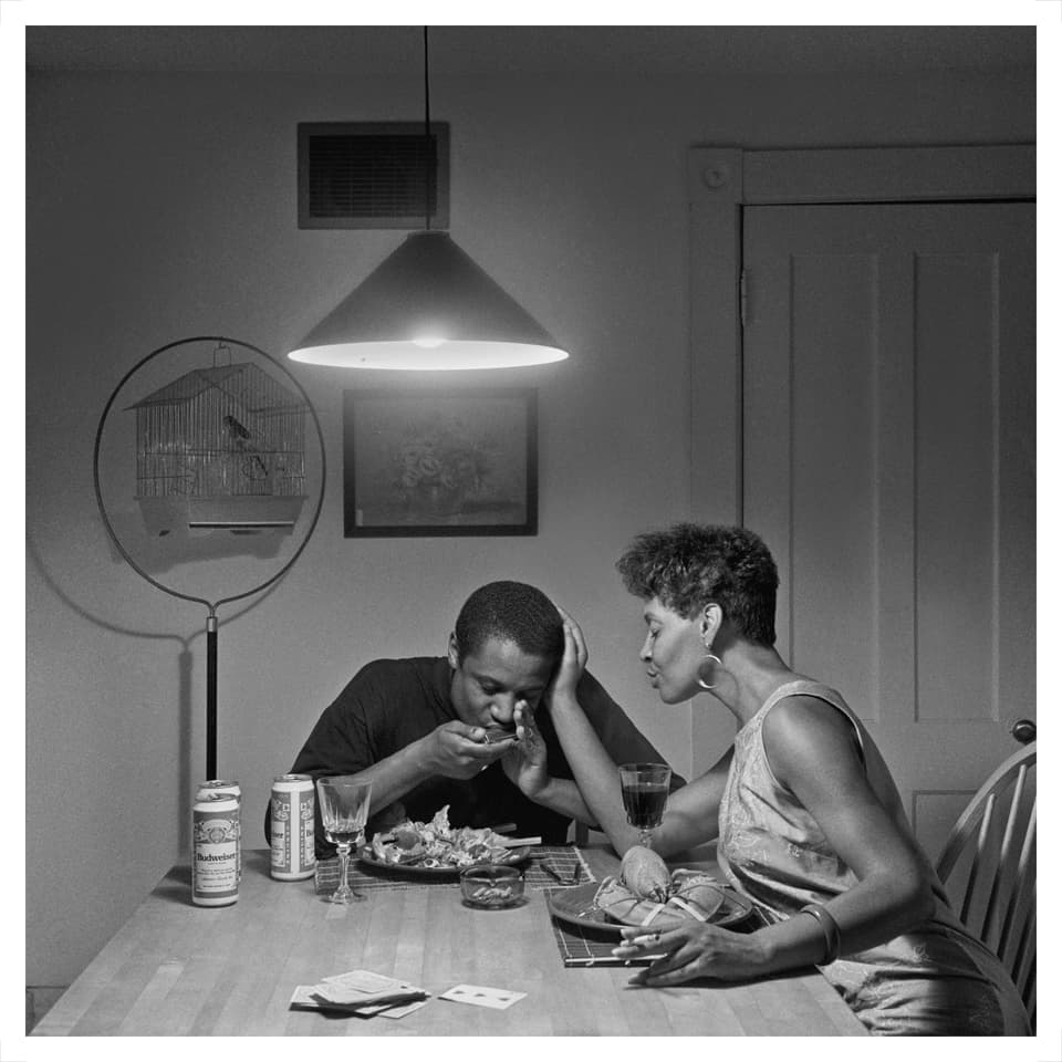 -Eine Frau und ein Mann essen am Küchentisch, sie streicht seinen Kopf
