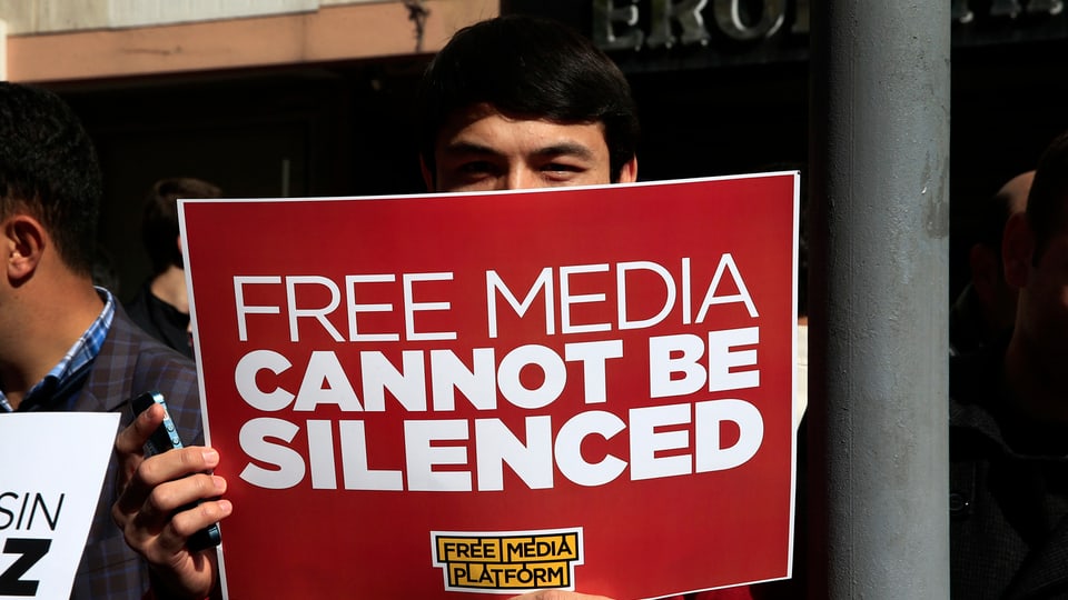 Symbolbild: Ein Mann hält ein Schild hoch, darauf heisst es: Freie Medien können nicht zum Schweigen gebracht werden.