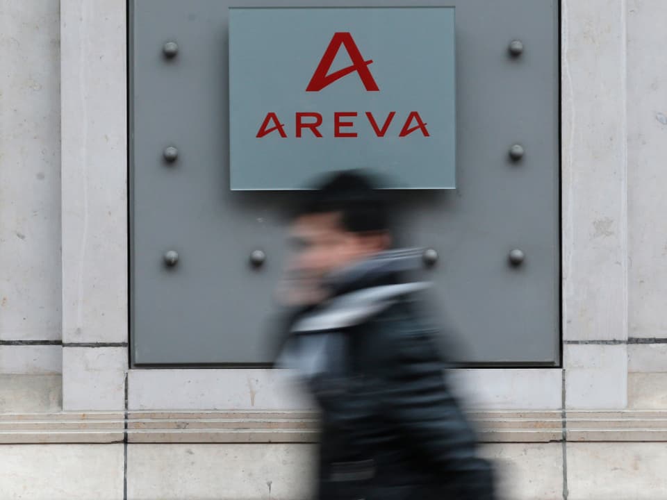 Eine Person läuft an einer Fassade mit dem Areva-Logo vorbei.