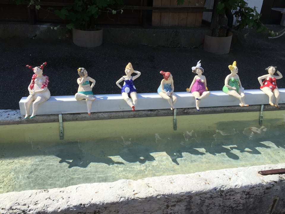 Frauenfiguren stehen auf dem Brunnenrand.