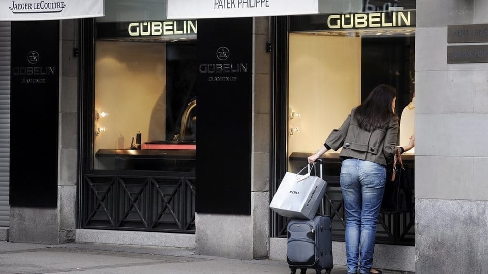 Eine Frau schaut in ein Schaufenster eines Schmuck-und Uhrengeschäftes in Zürich.