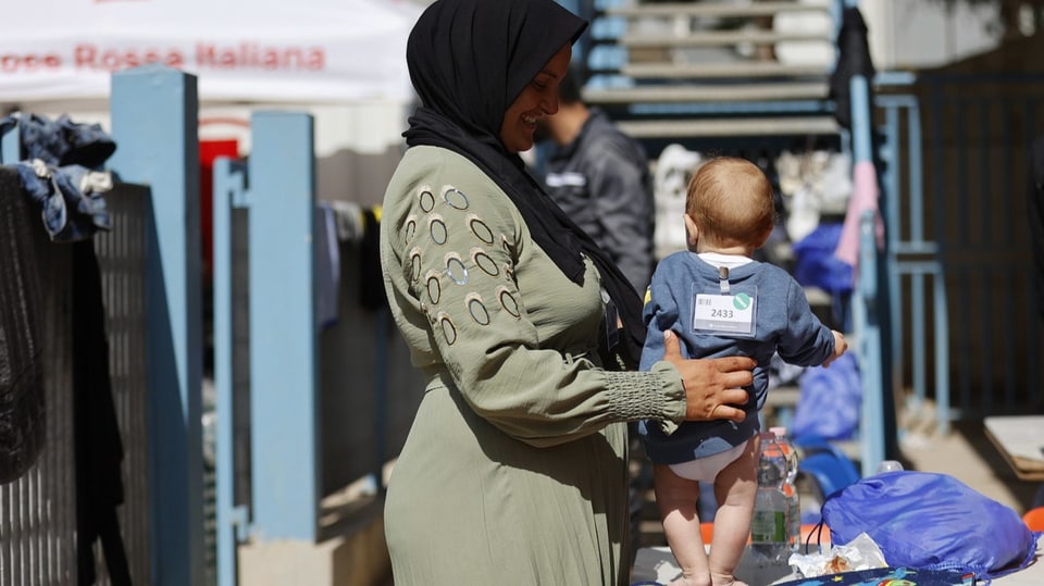 Eine Frau spielt mit einem Baby  im Erstaufnamelager auf der Insel Lampedusa.