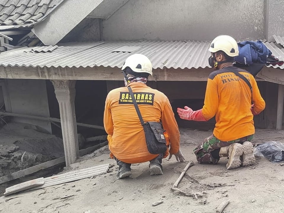 Rettungskräfte suchen bei einem Haus nach Verschütteten.