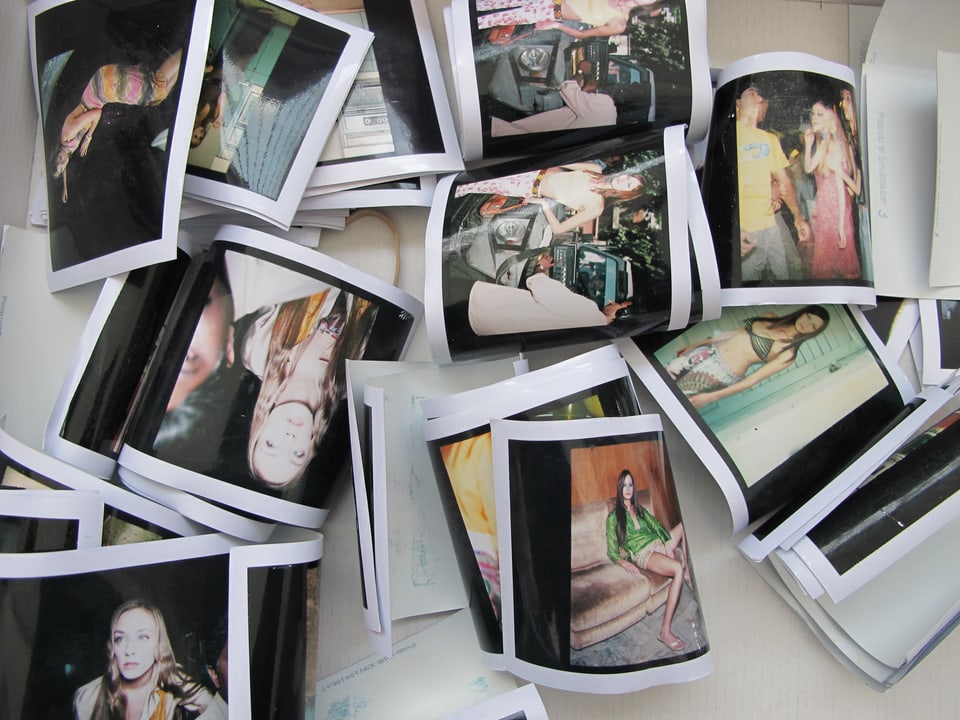 Kleine Abzüge von Hannes Schmids Fotos liegen durcheinander auf einem Tisch. 