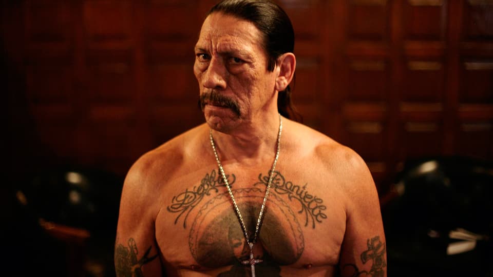 Trejo mit nacktem Oberkörper und grossem Tattoo auf der Brust.