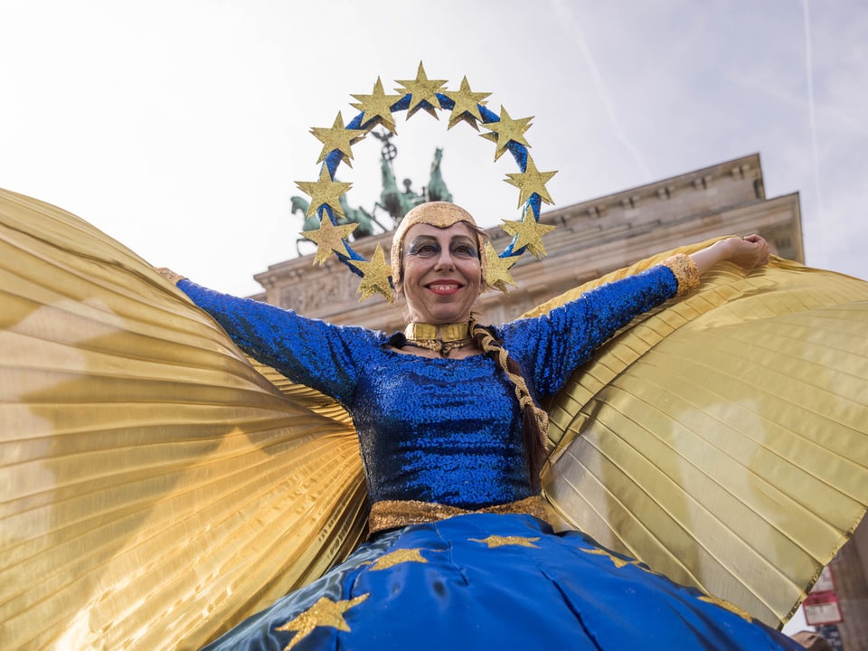 Eine als Europa verkleidete Frau vor dem Brandenburger Tor. 