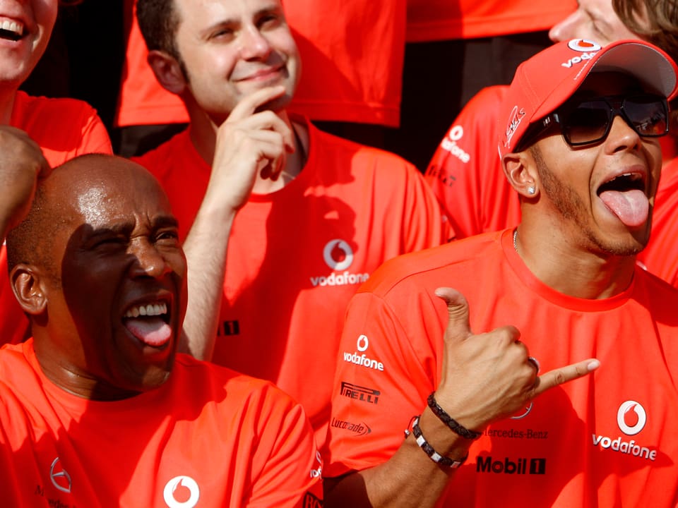Lewis Hamilton macht neben seinem Vater Anthony das Victory-Zeichen.