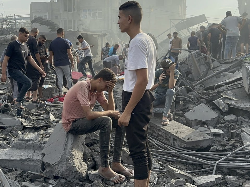 Zwei junge Männer in den Trümmern eines zerstörten Hauses.