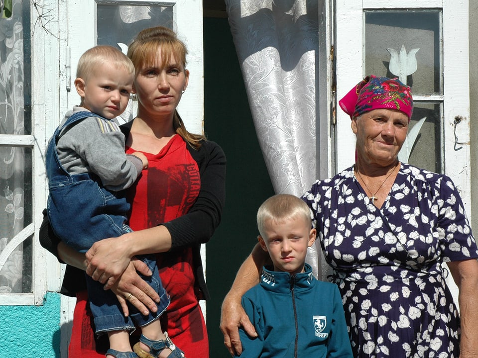 Die Mutter, diie Grossmutter und die zwei Söhne posieren vor dem Haus fürs Foto.