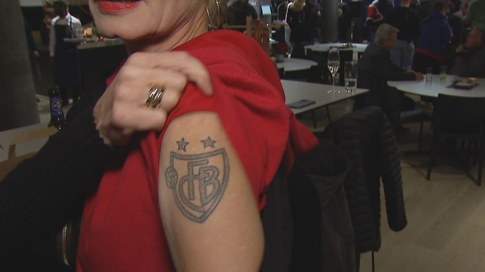 Ein Frau zeigt ihren tätowierten Oberarm mit dem FCB-Logo.