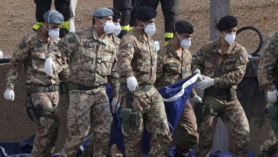 Italienische Soldaten tragen einen Leichensack
