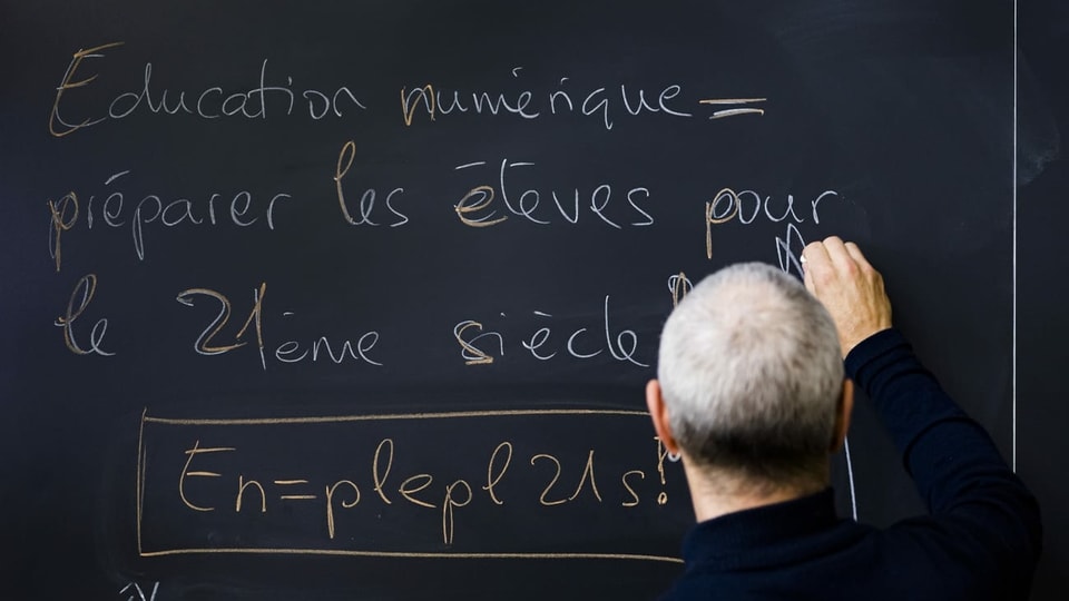 Mann schreibt etwas auf Französisch an eine Wandtafel