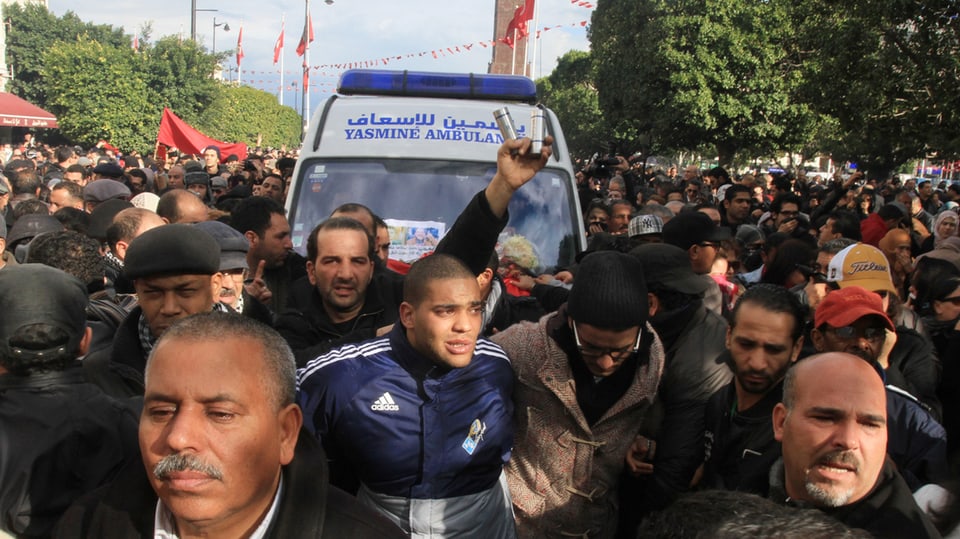 Demonstranten begleiten das den Leichnam von Chokri Belaïd transportierende Fahrzeug.