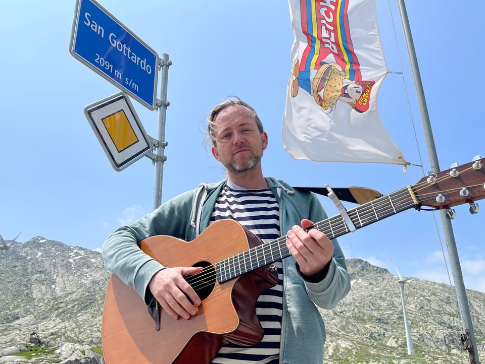 Christoph Trummer vertritt die Deutschschweiz. Christoph Trummer schaut nicht direkt ins Bild. Er steht vor einer dunklen Holzwand und trägt ein schwarzes Shirt.