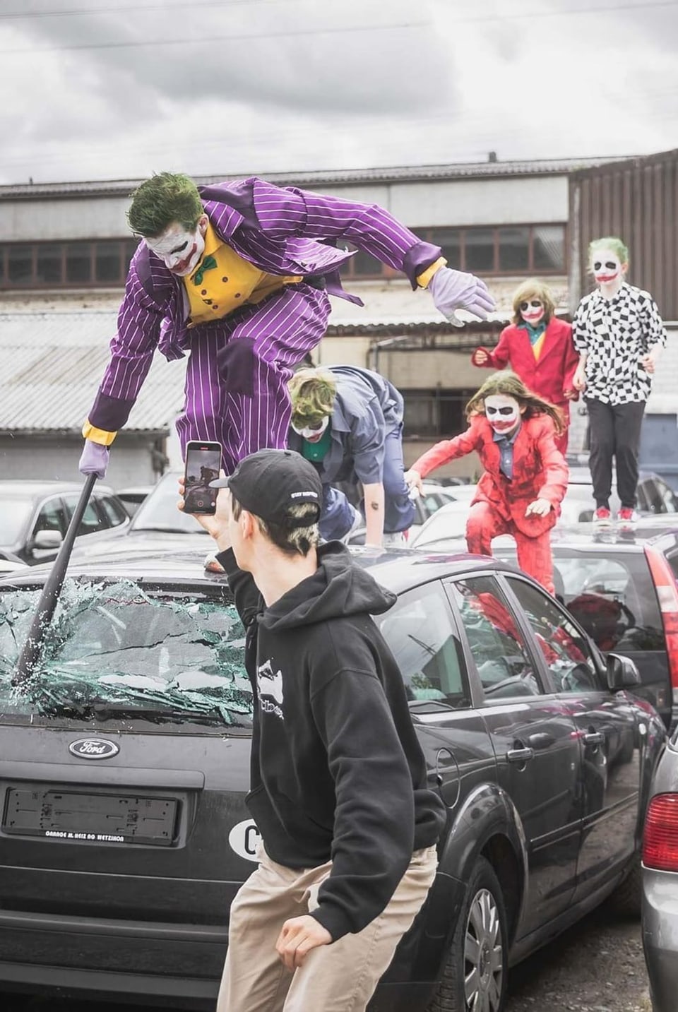 Mann filmt, wie Nicolas Huber und Kinder über ein Auto rennen. 