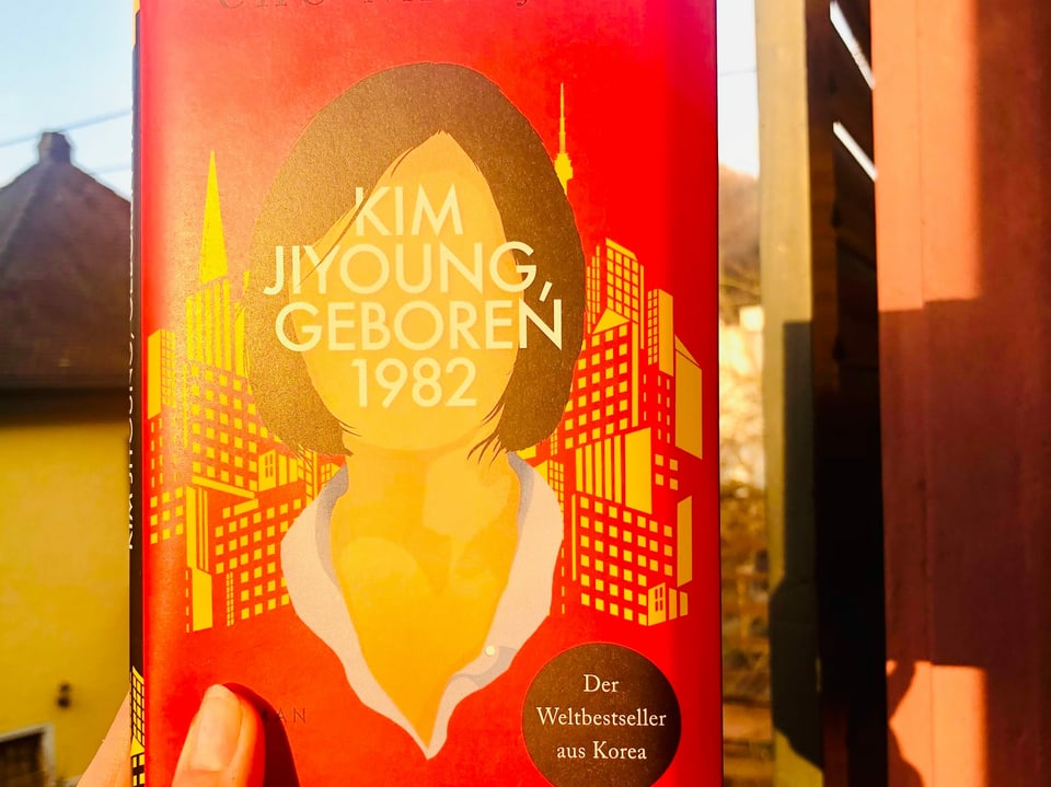 Annette König hält das Buch «Kim Jiyoung geboren 1982» von Cho Nam-Joo an die Sonne