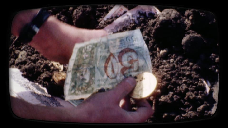Alte Geldscheine und Münzen werden aus der Erde ausgegraben.
