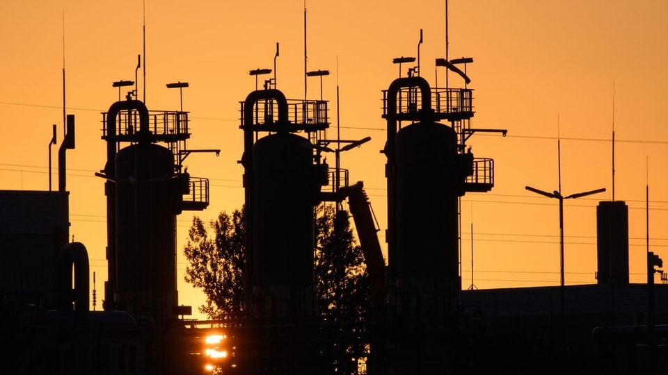 Die Sonne geht hinter den technischen Anlagen eines Gasspeichers in Deutschland auf. Hintergrund ist orange