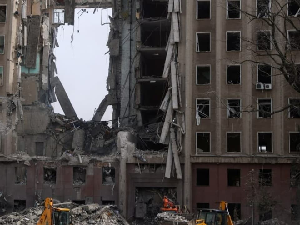 Rettungskräfte stehen in Mykolaiv vor einem zerstörten ukrainischen Regierungsgebäude