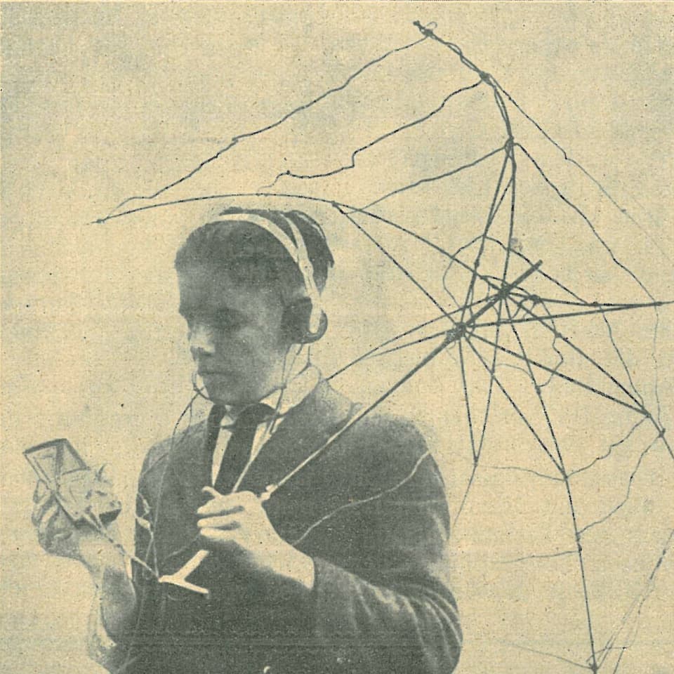 Junge mit ausrangiertem Gerüst eines Regenschirmes, Empfänger in der Hand und Kopfhörer. 