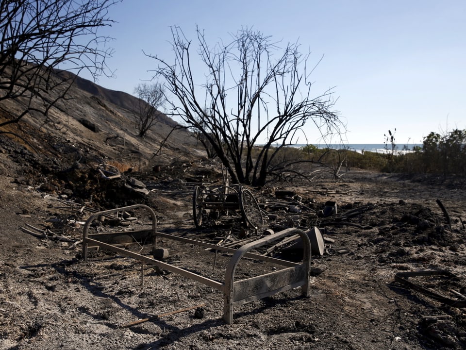 Ein Bettgestell in einer verbrannten Landschaft. 