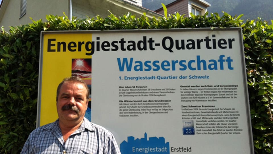 Werner Zgraggen steht vor einem Schild auf dem das Energiestadt-Quartier erklärt wird.