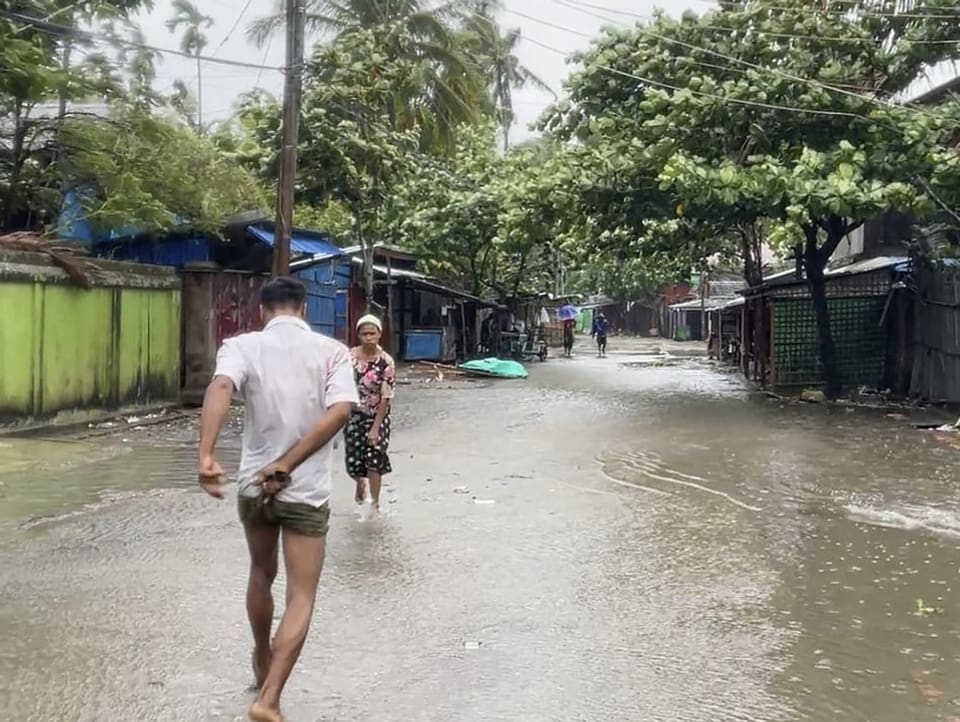 Menschen gehen über eine überflutete Strasse